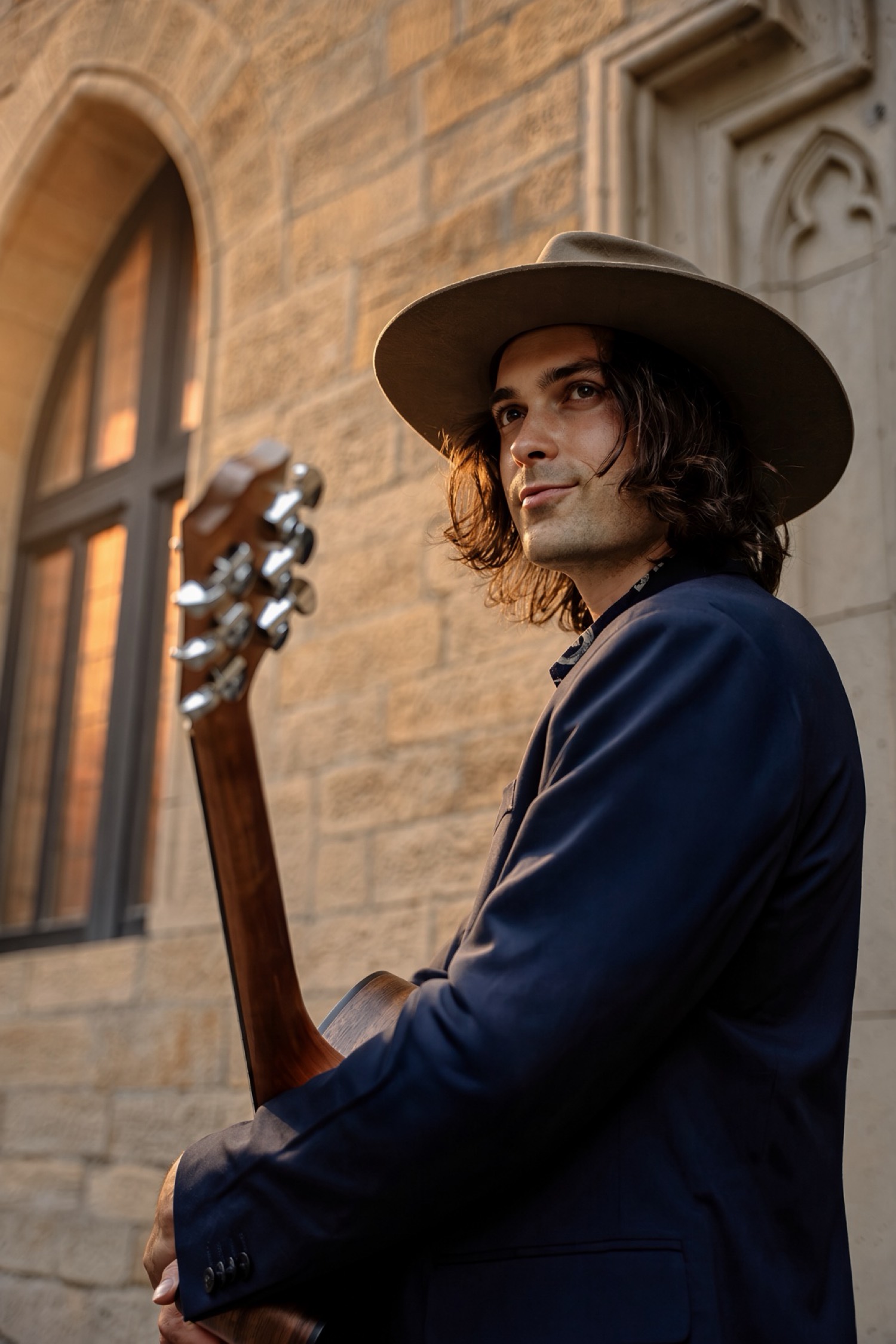Luke Greenstone vor historischem Sandstein, Gitarre im Arm