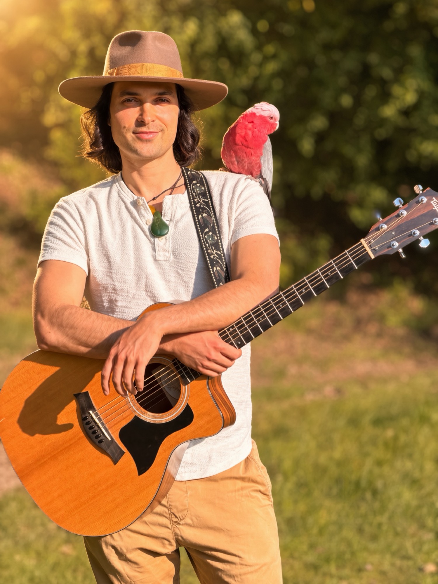 Luke Greenstone mit Bella, dem rosa Kakadu, und Gitarre